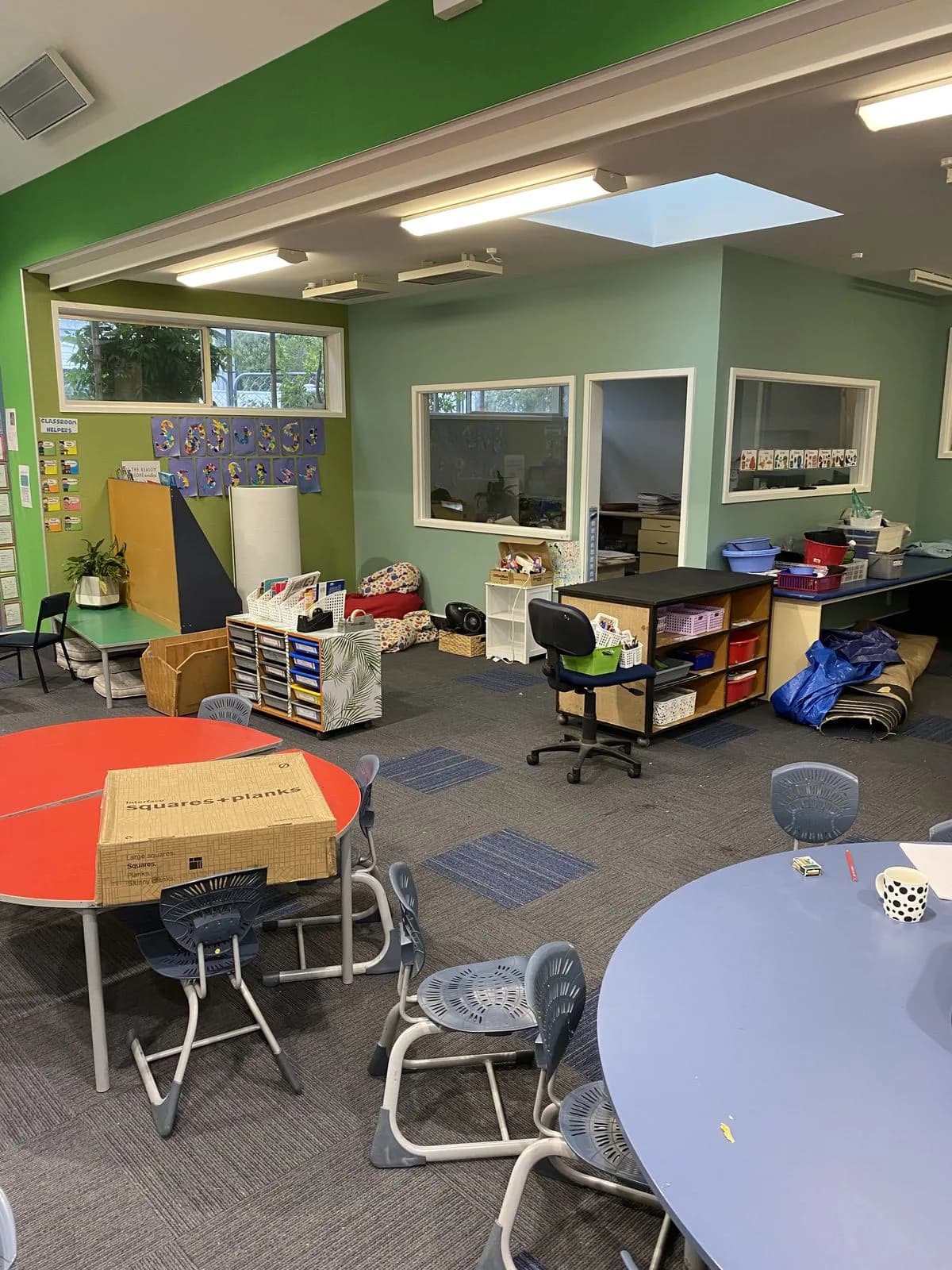 Green and blue acoustic walls with colourful tables and patterned carpet at Hampden Street School