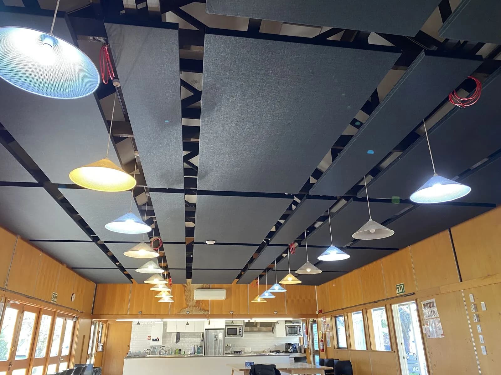 Finished black and grey acoustic panels on exposed ceiling battens above the Hopepa kitchen and timber walls