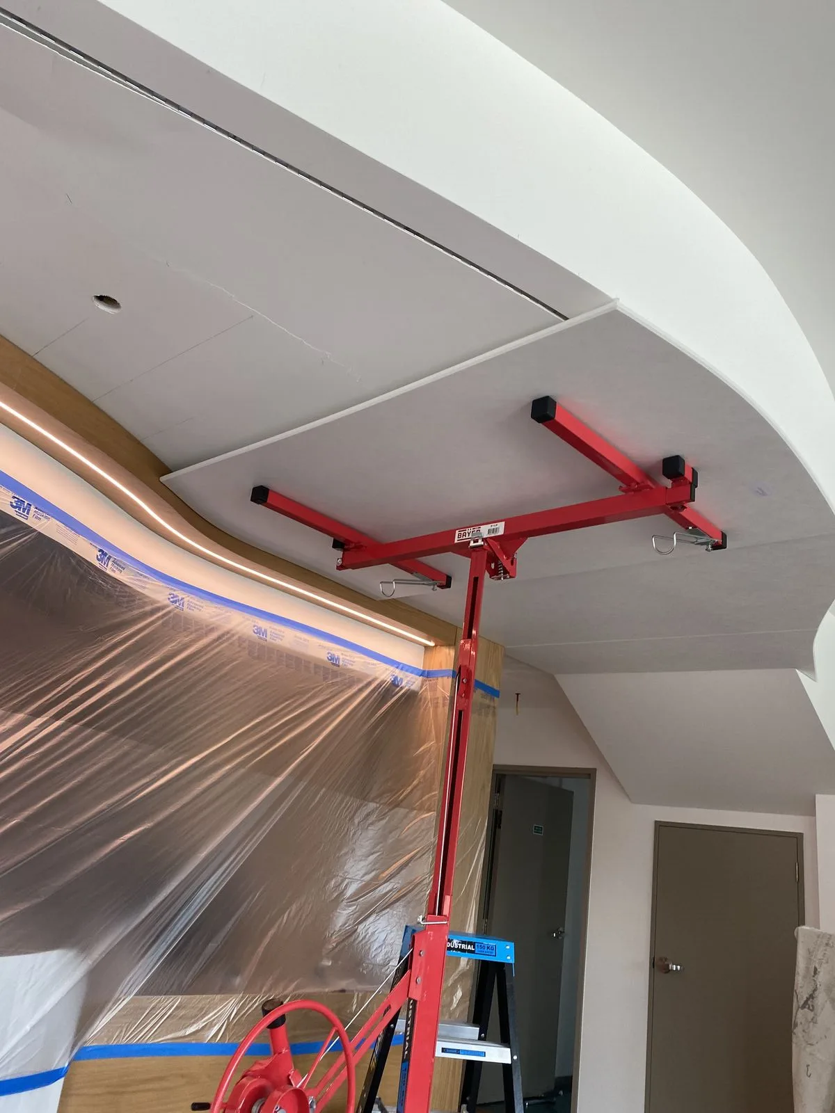 Curved ceiling install supported by red props and plastic sheeting at Riccarton Doctors